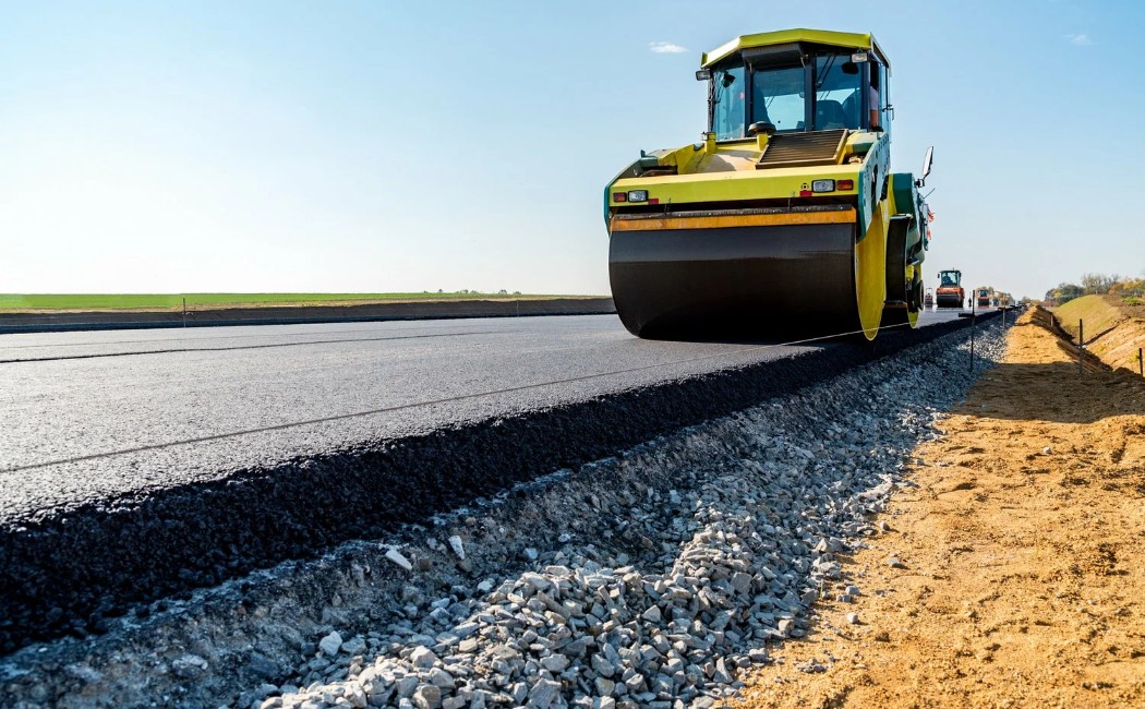 A road roller machine compacting freshly laid asphalt, showcasing professional asphalt work services for smooth and long-lasting road construction